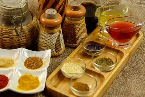Different types of spices in different containers on wood and canvas Stock Photos
