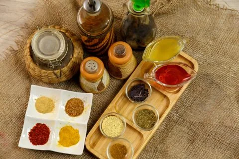 Different types of spices in different containers on wood and canvas Stock Photos