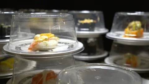 Different types of sushi and sashimi on plates are moving on a conveyor belt. Stock Footage 220138147