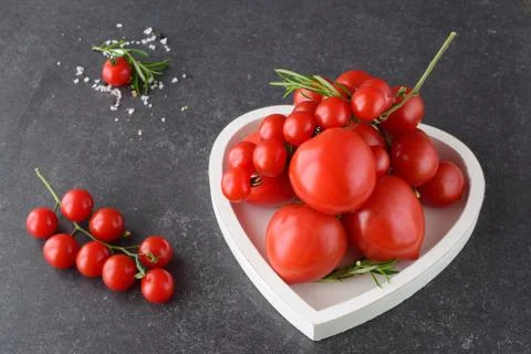 Different types of tomatoes on branches in heart shaped tray Stock Photos