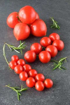 Different types of tomatoes on branches with rosemary and sea salt. Stock Photos