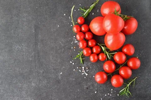 Different types of tomatoes on branches with rosemary and sea salt. Stock Photos