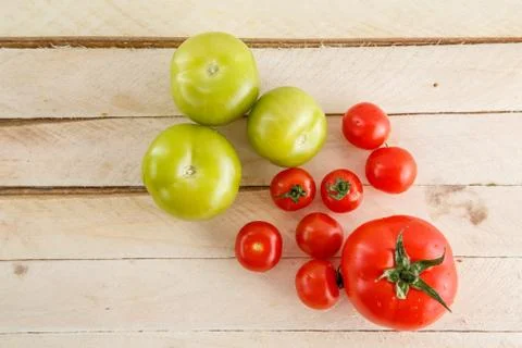 Different types of tomatoes on a light wooden background Stock Photos