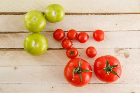 Different types of tomatoes on a light wooden background Stock Photos