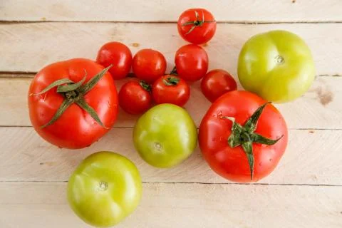Different types of tomatoes on a light wooden background Stock Photos