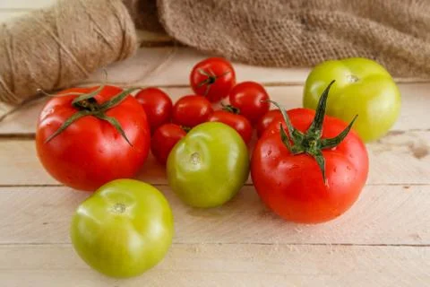 Different types of tomatoes on a light wooden background Stock Photos