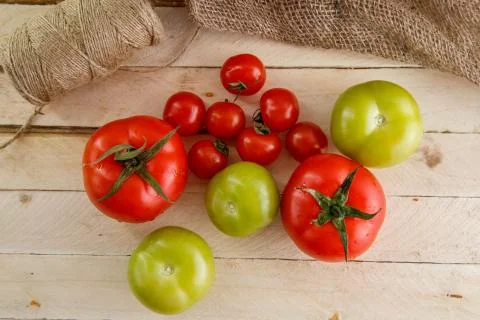 Different types of tomatoes on a light wooden background Stock Photos