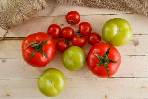 Different types of tomatoes on a light wooden background Stock Photos