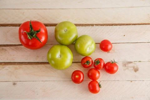 Different types of tomatoes on a light wooden background Stock Photos