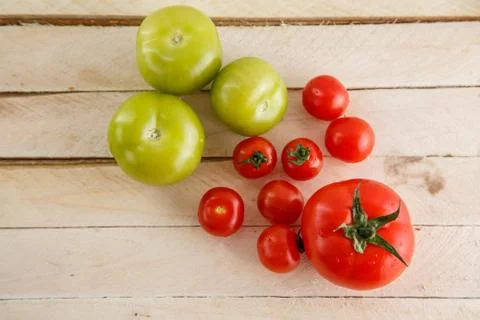 Different types of tomatoes on a light wooden background Stock Photos