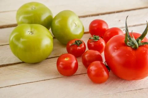 Different types of tomatoes on a light wooden background Stock Photos