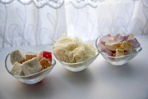 Different types of traditional sweets displayed in glass bowls on a white t.. 库存照片