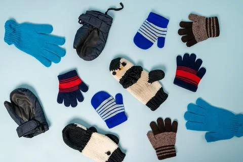 Different types of winter gloves and mittens on a blue background Stock Photos