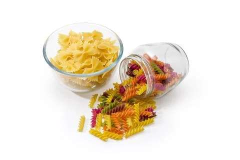 Different uncooked colored pasta in jar and in glass bowl Stock Photos