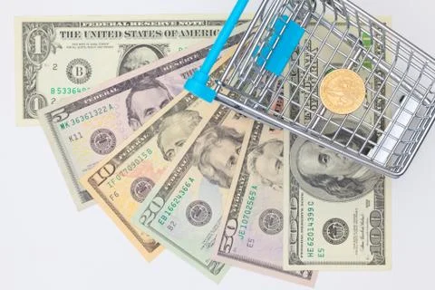 Different us dollar banknotes and empty shopping trolley. Photos
