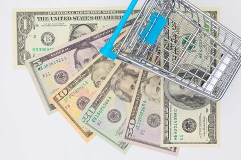 Different us dollar banknotes and empty shopping trolley. 库存照片