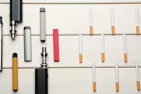 Different vaping devices and cigarettes on white wooden table, flat lay. Smok Stock Photos