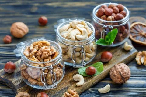 Different varieties of nuts in glass jars. Stock Photos