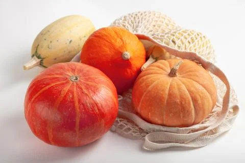 Different varieties of pumpkins in a string bag on a white background Stock Photos