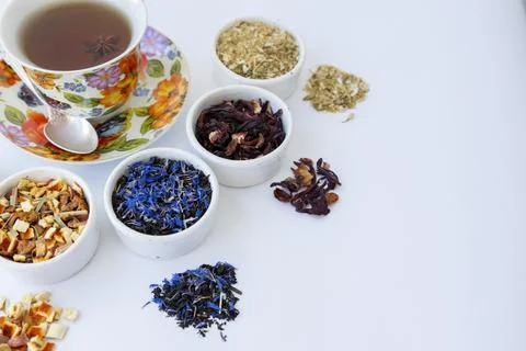 Different varieties of tea are scattered on a white table. A cup of tea Stock Photos