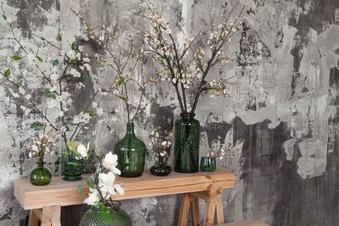 Different vases with spring flowers in front of grey concrete wall Stock Photos