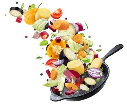 Different vegetables falling into frying pan on white background Stock Photos