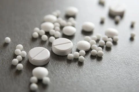 Different white tablets are found on the surface. Stock Photos