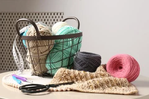 Different yarns, crochet hooks, pattern sample and scissors on beige table Stock Photos