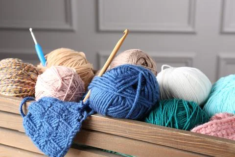 Different yarns, pattern sample and crochet hooks in wooden crate, closeup Stock Photos