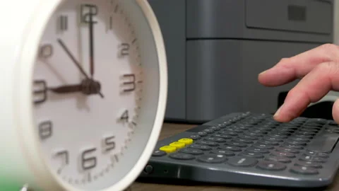 Differential focus – fingers on computer keyboard, switching to clock at 9am. Stock Footage 155960712
