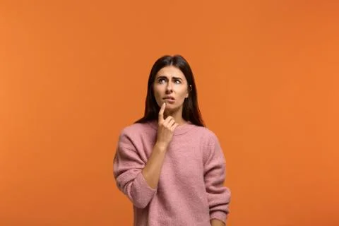 Difficult decision. Image of hesitant beautiful woman in pink sweater, holds  Stock Photos