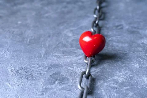 Difficult love relationship concept with a heart symbol and metal chain. Stock Photos
