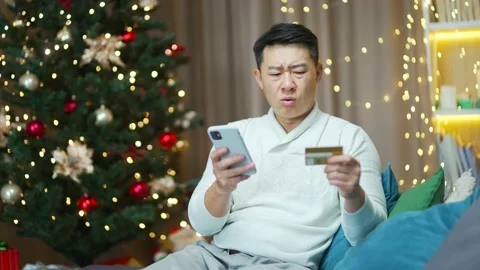 Difficulties with payment. Dissatisfied Asian man trying to make a purchase in  Stock Footage 219912612