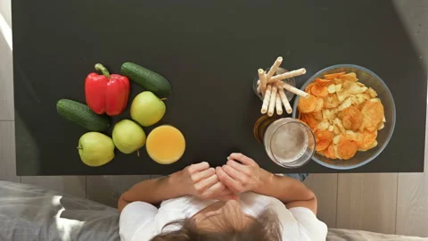 The difficulty of choosing between a healthy and unhealthy diet. A woman chooses Stock Footage 130786109