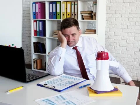 Difficulty managing a team. Sad manager and loudspeaker on the table. Stock Photos