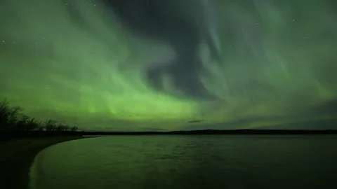 Diffuse Aurora Borealis over a rippled lake Stock Footage 250293216
