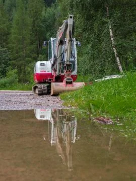 Digger and its reflection in puddle Stock Photos