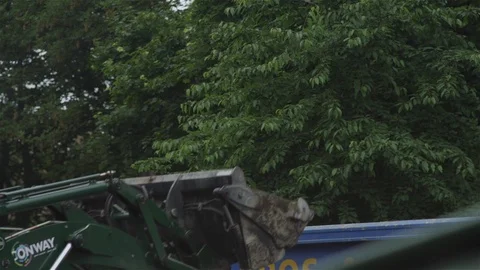 Digger and moving earth and emptying bucket into dump truck c/up Stock Footage 93207604