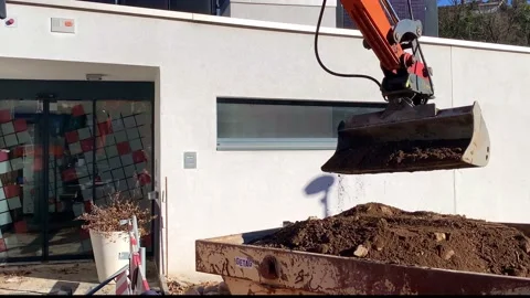 Digger Putting Ground in a Container Close to a House in a Sunny Day Video stock 191936430
