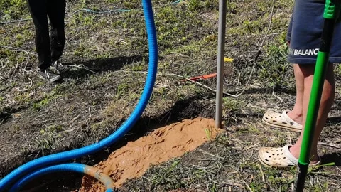 Digging a hole for water pipe installation in a field with tools and equipment d 動画素材 336126906