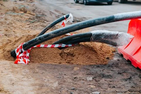 Digging at a road site, exposing cables and dirt surrounding them. Bright safety Stock Photos