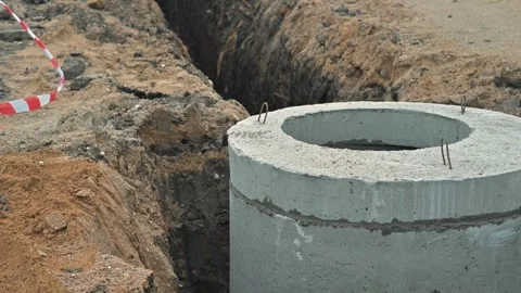 Digging a trench to install concrete drainage pipes. The site is busy with 库存影片 344675686