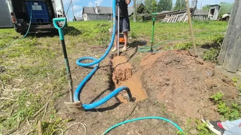 Digging a trench for water pipe installation in the countryside during summer Stock Footage 336158842
