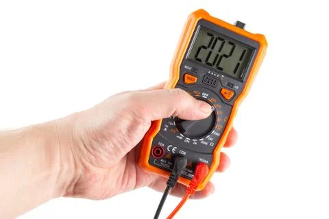 Digit 2021 on lcd screen of digital electrical multimeter in left hand, isola 库存照片