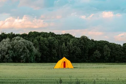 Digital 3D render of a yellow camping tent on a rural valley near green trees Illustrazione stock