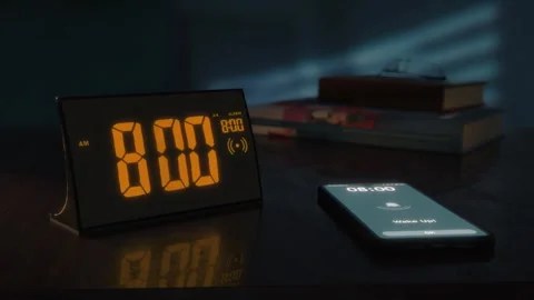 Digital alarm clock with orange clockface and the smartphone waking up at 8 AM Video stock 254784647