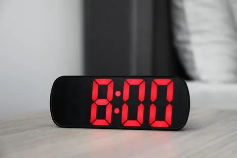 Digital alarm clock showing 8:00 o'clock on bedside table indoors Stock Photos