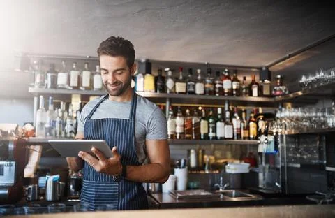 The digital bartender. a young man using a digital tablet while working behind a Stock Photos