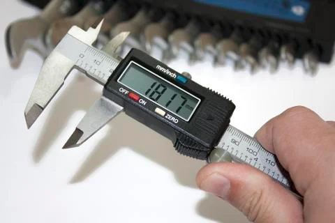 Digital calliper in the hand with tools in the background Stock-Fotos