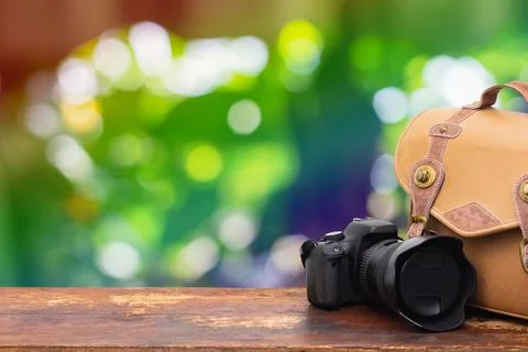 Digital camera and camera bag on an old brown wooden table.Abstract nature gr Stock Photos